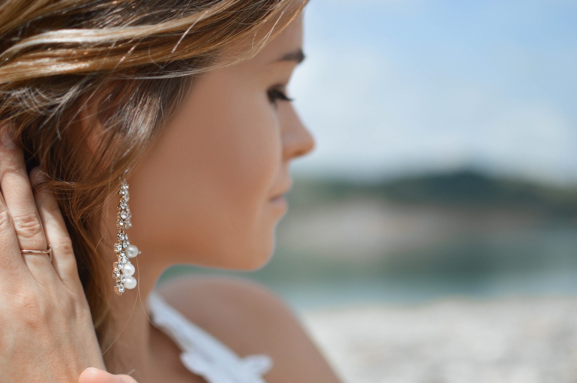 A close-up of a woman’s profile, accentuated with delicate diamond and pearl drop earrings.