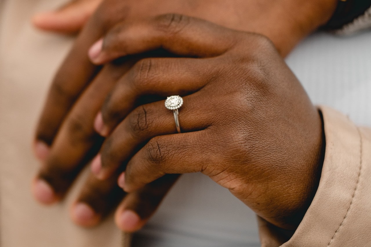 A halo diamond engagement ring on a white gold band on a woman’s hand