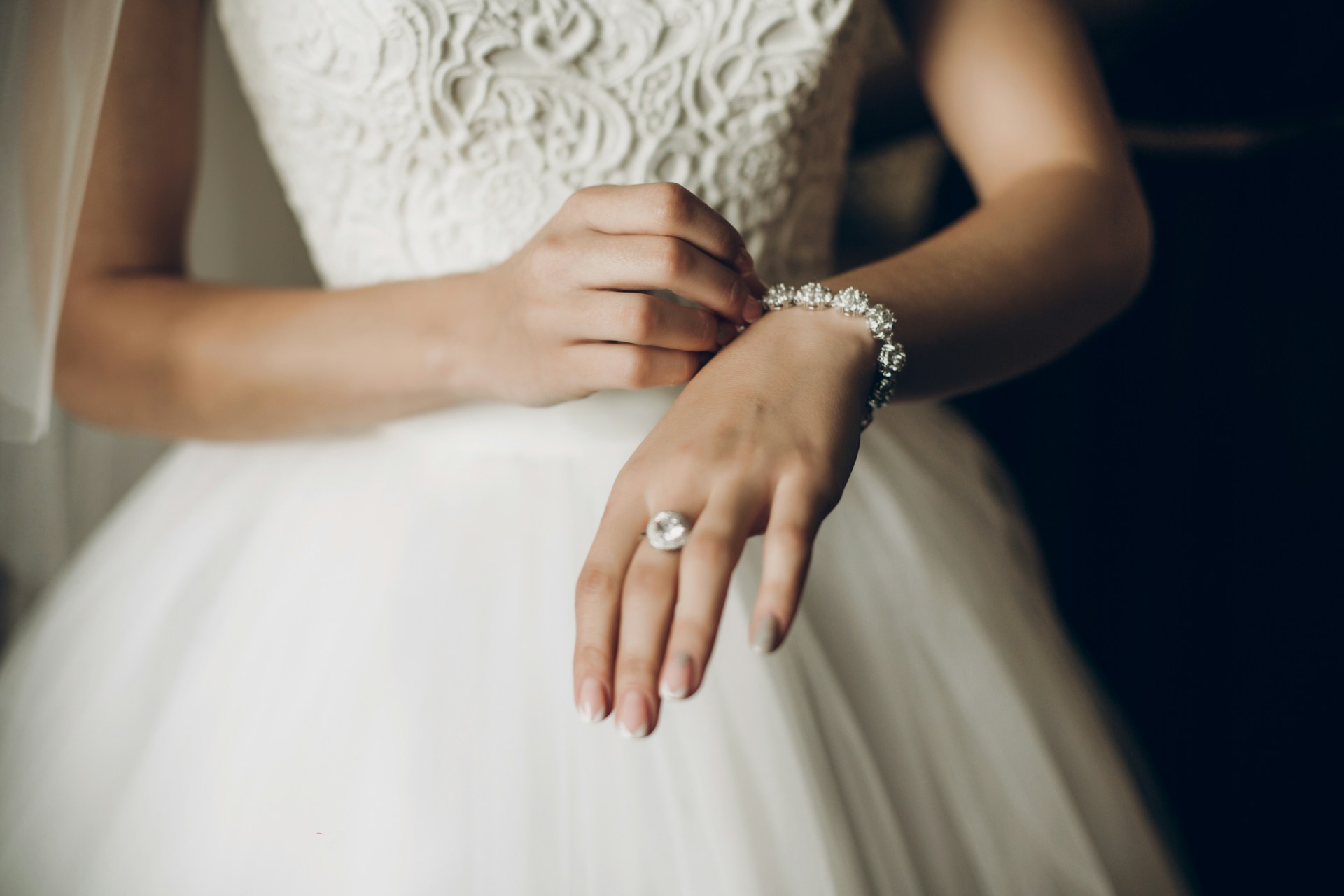 a bride holding out her arm and showing off a diamond fashion ring and diamond bracelet