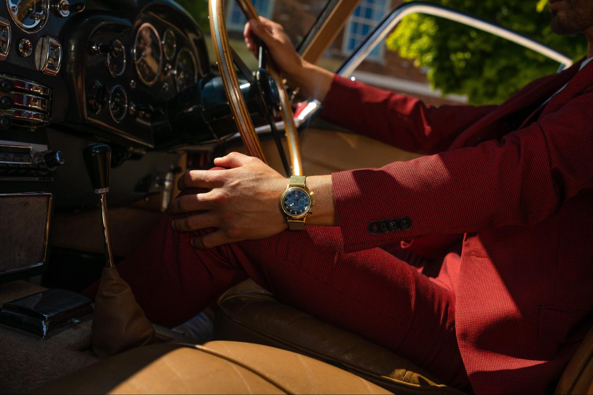 A well-dressed man wearing a luxury wrist watch as he drives a vintage car.