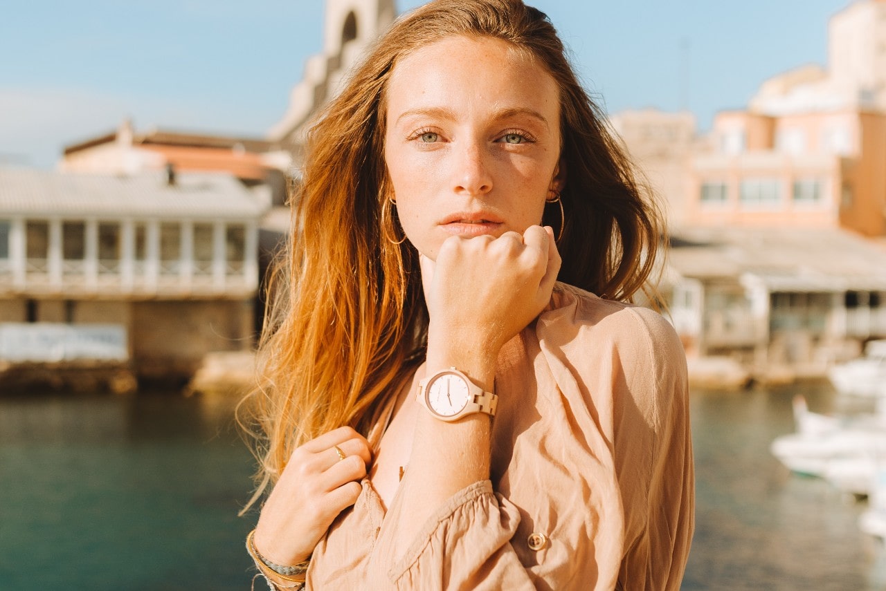 A fashionable young woman wearing an elegant watch at a pier.