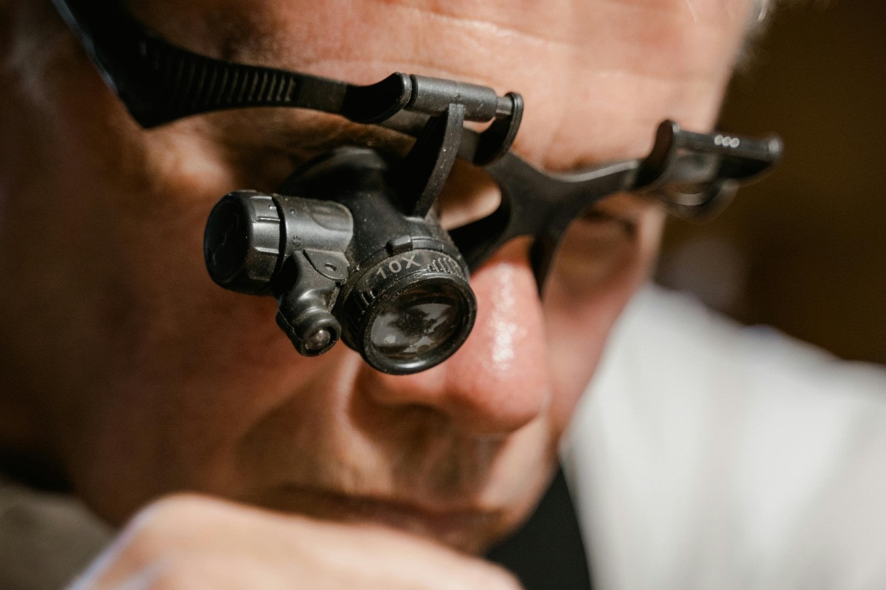 A watchmaker wearing magnifying equipment as he maintains a timepiece.