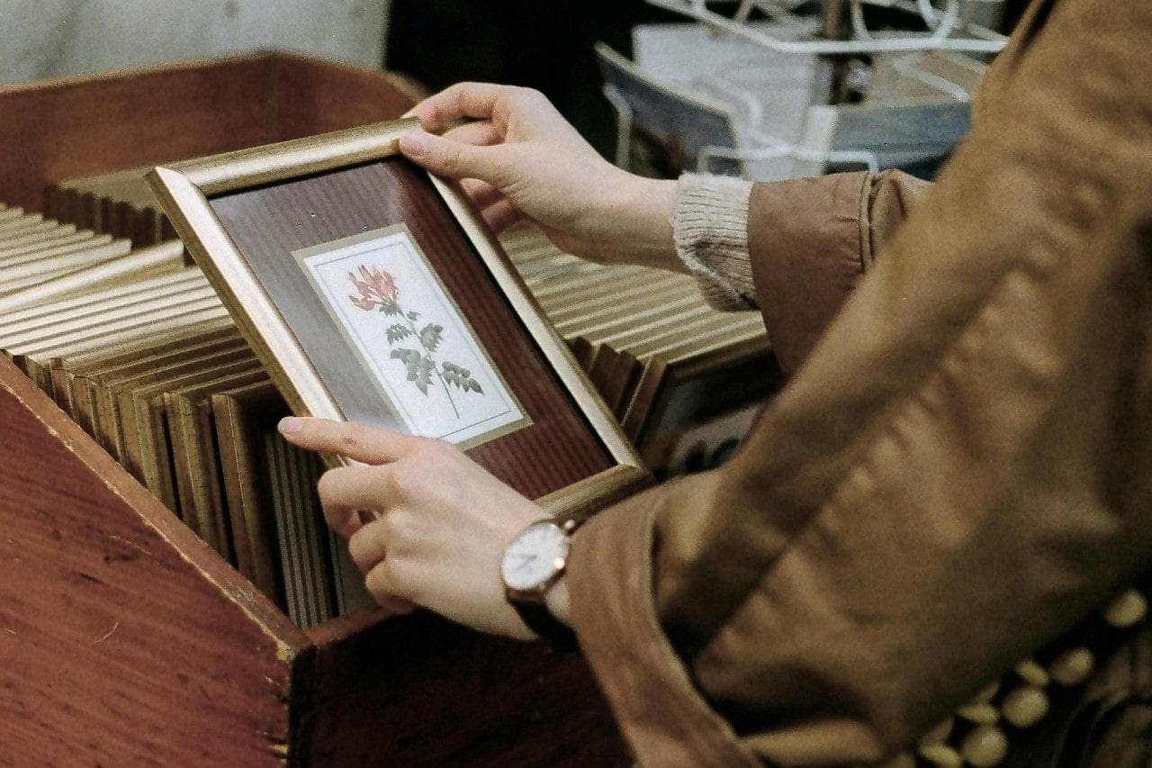 A person holding a picture frame and wearing a classic dress watch.