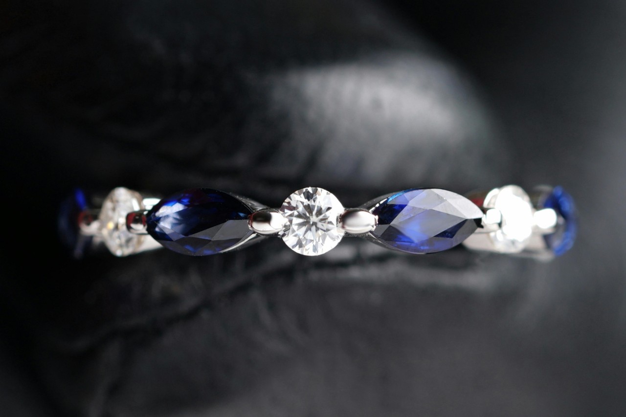 close up image of a white gold wedding band with sapphires and diamonds