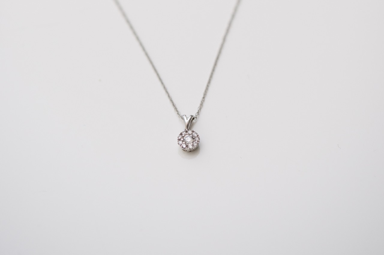 A close-up of a delicate pendant necklace on a pale backdrop.