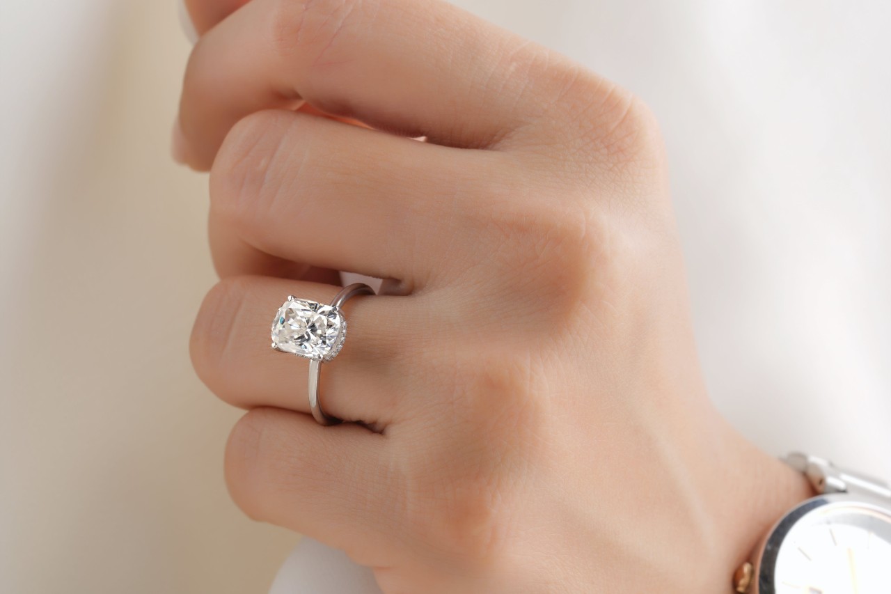 close up image of a person’s hand wearing a solitaire radiant cut engagement ring
