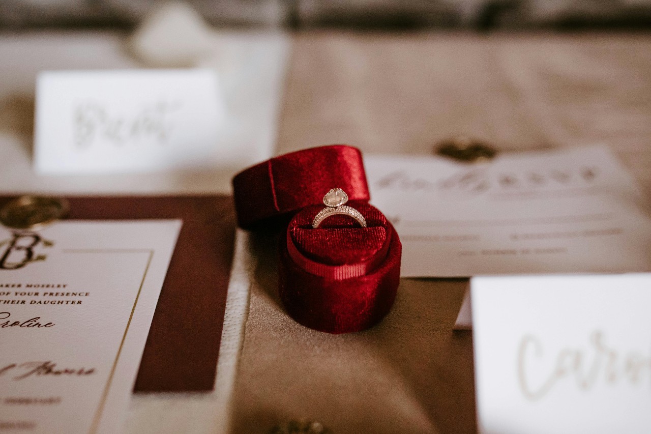 a yellow gold engagement ring sitting in a red ring box on a lavishly set table