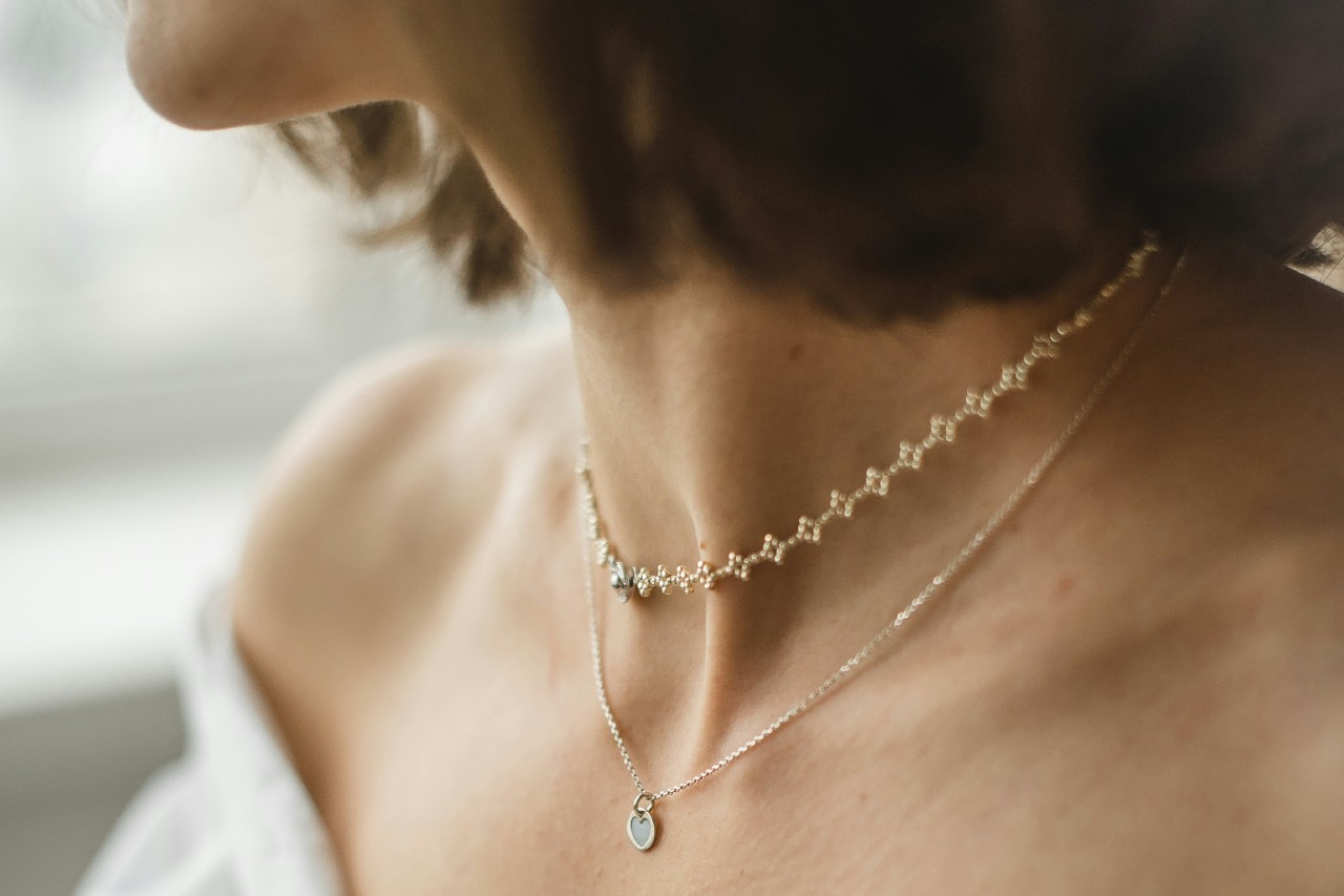 close up image of a woman’s neckline adorned with two yellow gold fine chain necklaces.